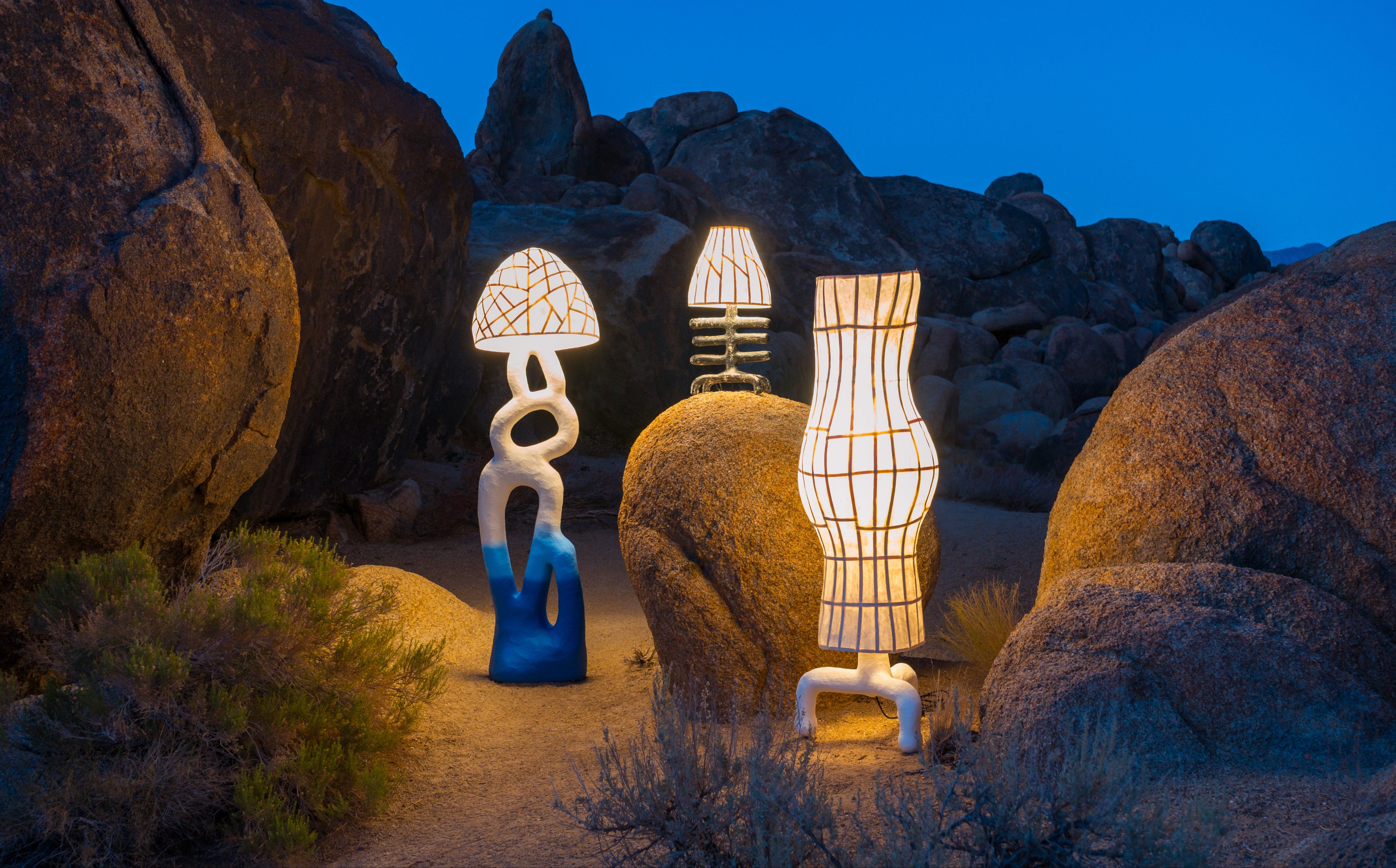 Three unique lamps illuminated in a Californian high desert landscape at night.